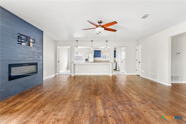 unfurnished living room with hardwood / wood-style flooring, ceiling fan, and a fireplace