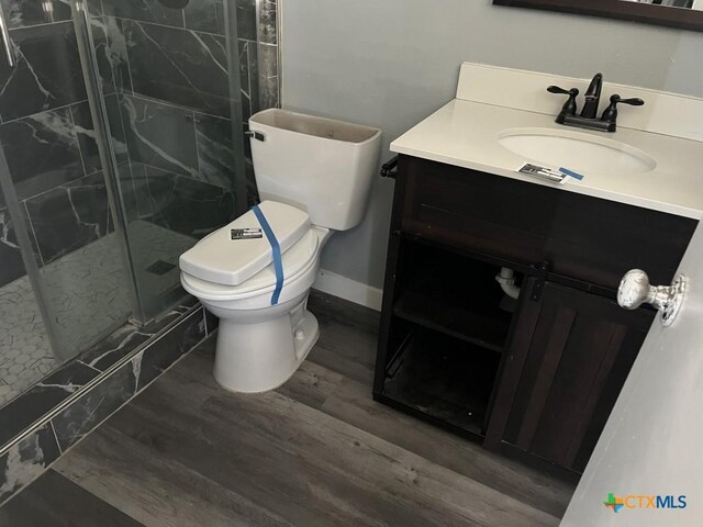 bathroom featuring hardwood / wood-style flooring, vanity, an enclosed shower, and toilet