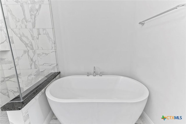 4201 Arques Ave, Round Rock, TX 78681 - full bathroom with a soaking tub, marble look tiles, and baseboards