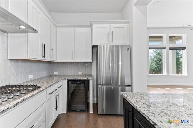 4201 Arques Ave, Round Rock, TX 78681 - kitchen featuring appliances with stainless steel finishes, beverage cooler, wall chimney range hood, white cabinetry, and decorative backsplash