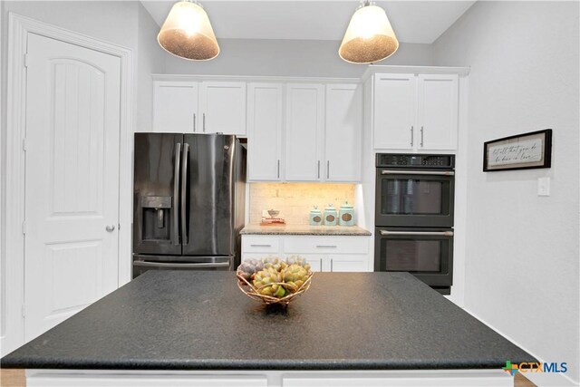 kitchen with black double oven, stainless steel fridge, hanging light fixtures, and white cabinets