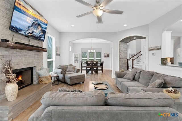 living room featuring ceiling fan, a wealth of natural light, a fireplace, and light wood-type flooring