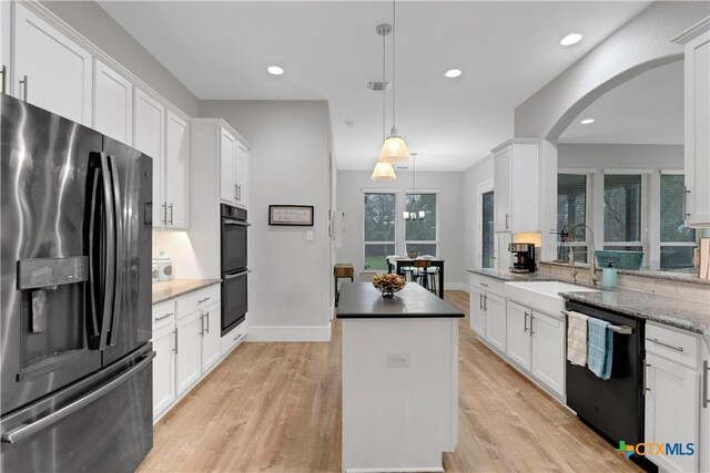 kitchen featuring hanging light fixtures, black appliances, and white cabinets