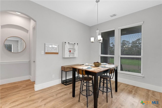 dining space with a wealth of natural light, a notable chandelier, and light hardwood / wood-style flooring