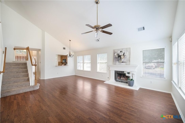 unfurnished living room with dark hardwood / wood-style flooring, ceiling fan with notable chandelier, and high vaulted ceiling