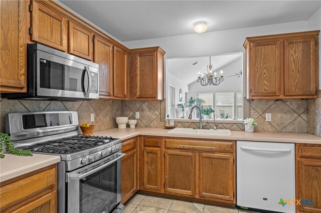 kitchen featuring sink, backsplash, white dishwasher, stainless steel range with gas cooktop, and a chandelier