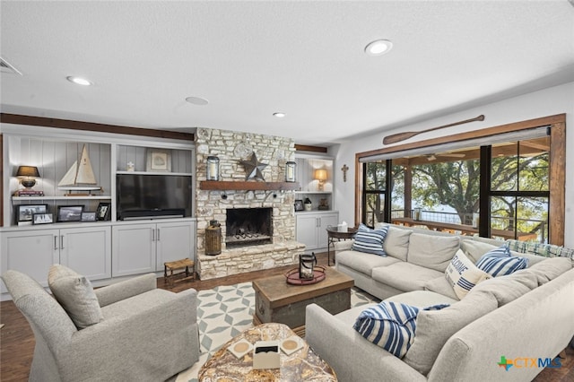 living area featuring recessed lighting, a stone fireplace, a textured ceiling, and wood finished floors