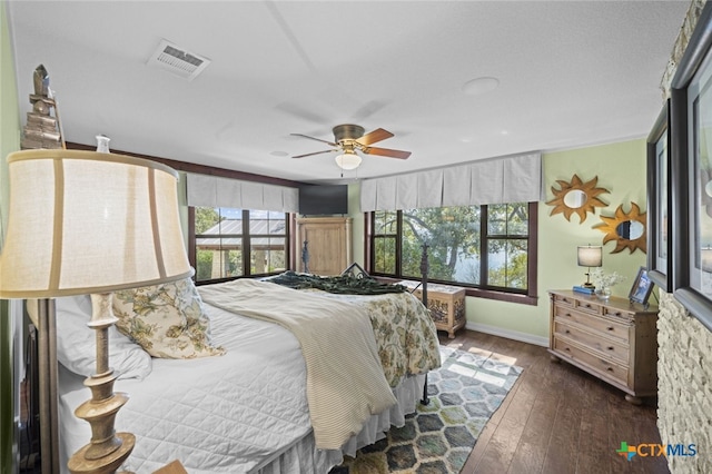 bedroom with baseboards, ceiling fan, visible vents, and dark wood-type flooring