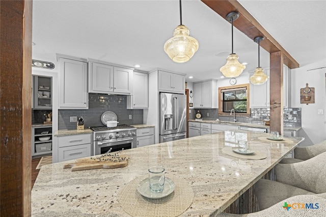 kitchen with light stone counters, premium appliances, a breakfast bar, a sink, and backsplash