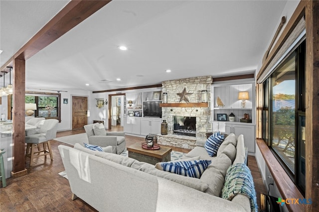 living room with recessed lighting, dark wood-style flooring, a wealth of natural light, and a stone fireplace