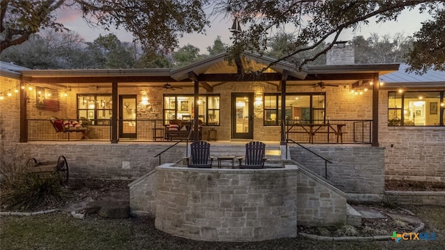 back of property at dusk featuring ceiling fan and a chimney