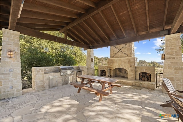 view of patio / terrace with grilling area, an outdoor stone fireplace, and an outdoor kitchen