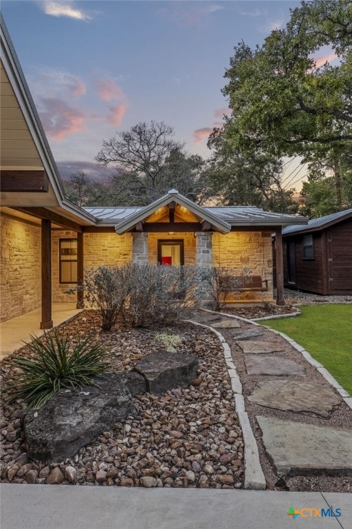 view of front of property with metal roof, stone siding, a standing seam roof, and a lawn