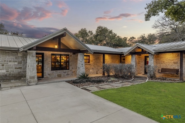 view of front of property with a standing seam roof, stone siding, and metal roof