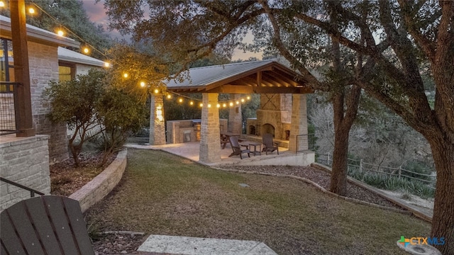 view of yard featuring a patio, an outdoor stone fireplace, a gazebo, and fence