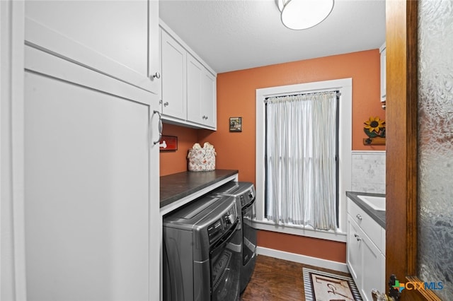 clothes washing area featuring dark wood finished floors, cabinet space, a textured ceiling, washer and dryer, and baseboards