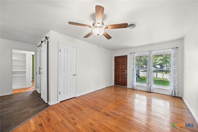 2307 Crescent Dr, Copperas Cove, TX 76522 - unfurnished bedroom featuring a barn door, wood finished floors, and ceiling fan