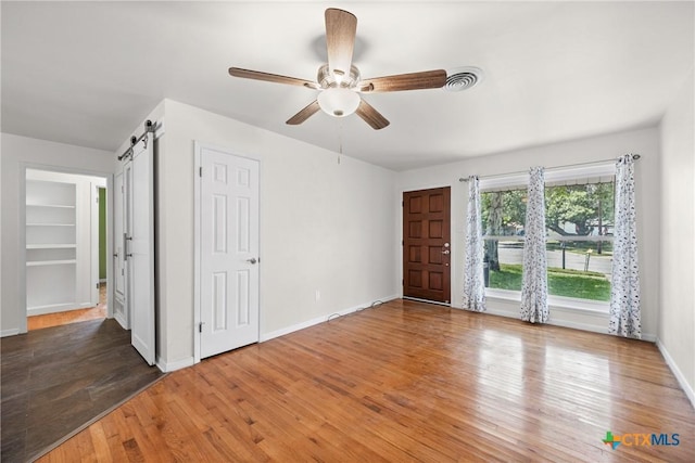 2307 Crescent Dr, Copperas Cove, TX 76522 - unfurnished bedroom featuring a barn door, wood finished floors, and a ceiling fan