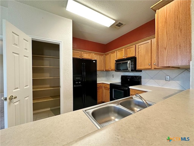4609 Golden Gate Dr, Killeen, TX 76549 - kitchen featuring black appliances, backsplash, light countertops, a textured ceiling, and brown cabinetry