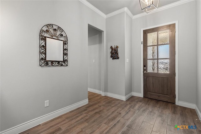 foyer with baseboards, wood finished floors, ornamental molding, and an inviting chandelier