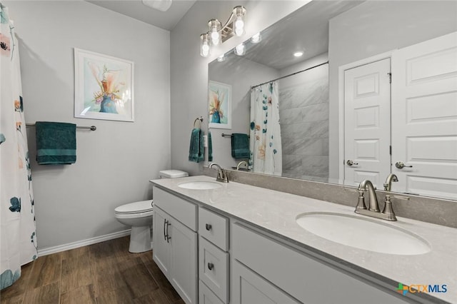 full bathroom with baseboards, a sink, toilet, and wood finished floors