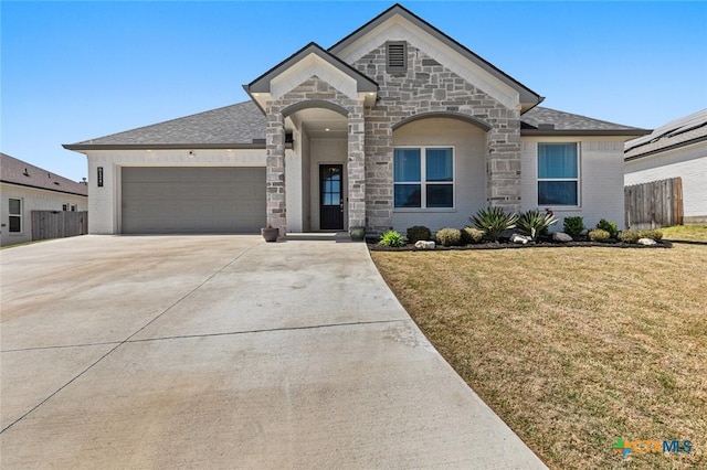 french country inspired facade featuring driveway, stone siding, fence, an attached garage, and a front lawn