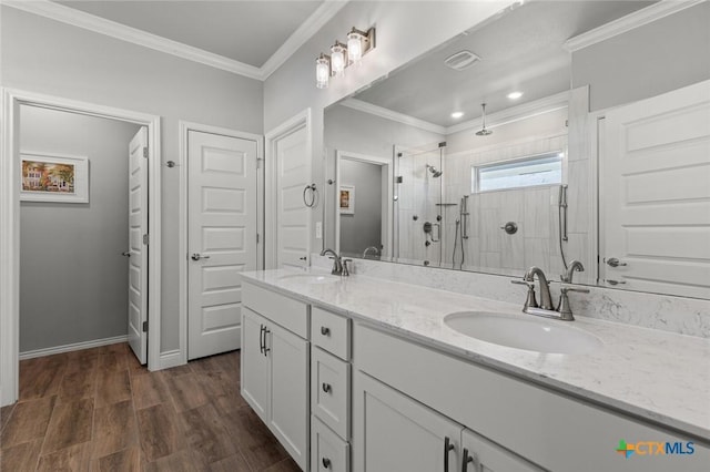 bathroom featuring crown molding, a sink, a shower stall, and wood finished floors