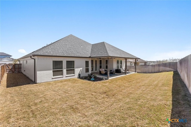 back of house with a fenced backyard, brick siding, a shingled roof, a yard, and a patio area