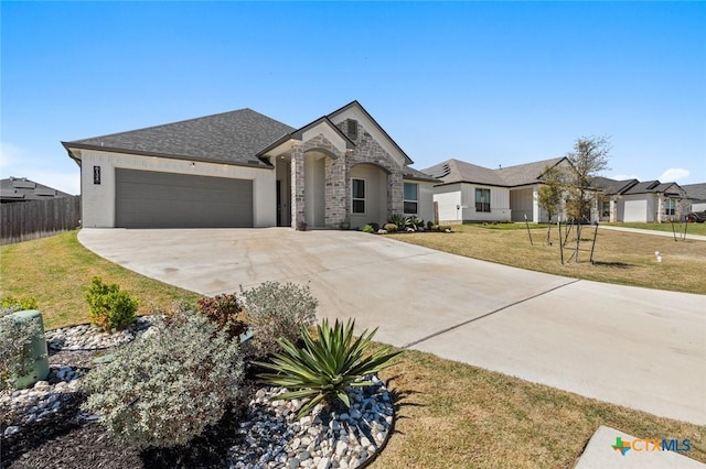 french provincial home featuring stone siding, fence, an attached garage, a front yard, and driveway