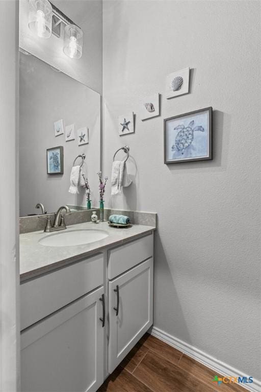bathroom featuring baseboards, wood finished floors, and vanity