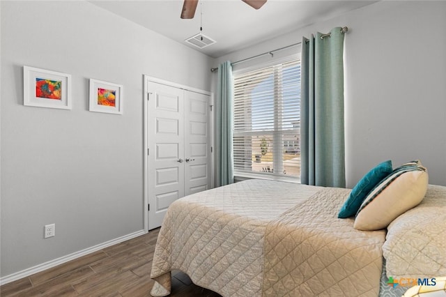 bedroom with a closet, visible vents, baseboards, wood finished floors, and a ceiling fan