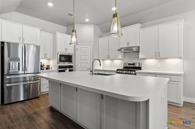 kitchen featuring a sink, appliances with stainless steel finishes, a center island with sink, under cabinet range hood, and visible vents