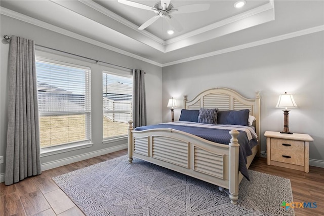bedroom with baseboards, ornamental molding, wood finished floors, recessed lighting, and a raised ceiling