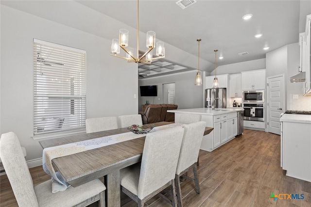 dining room featuring recessed lighting, visible vents, light wood-style floors, and a notable chandelier