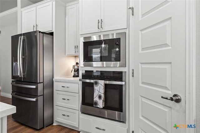 kitchen with white cabinets, light countertops, dark wood-style flooring, and appliances with stainless steel finishes