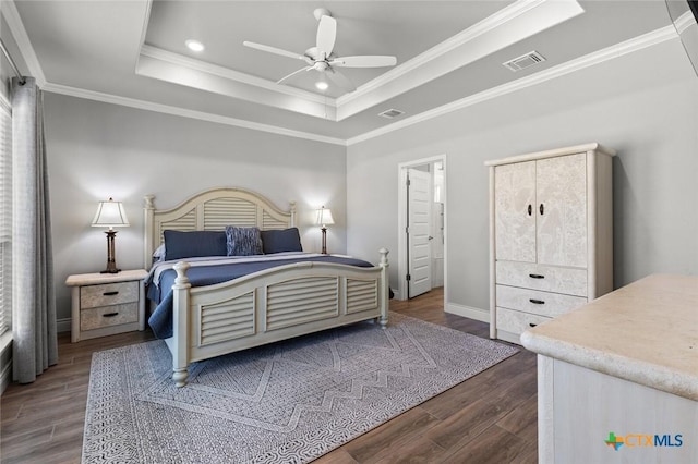 bedroom with a tray ceiling, visible vents, dark wood finished floors, and ornamental molding