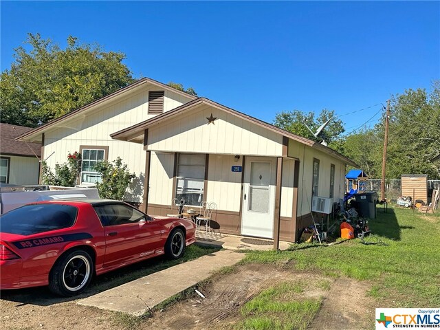 view of front of home with cooling unit and a front yard