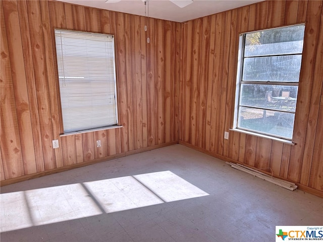 empty room featuring wood walls and ceiling fan