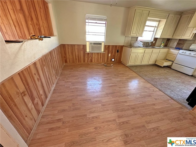 kitchen with white stove, plenty of natural light, light wood-type flooring, and cream cabinets