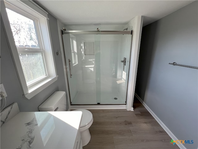 bathroom with hardwood / wood-style floors, toilet, an enclosed shower, and a wealth of natural light