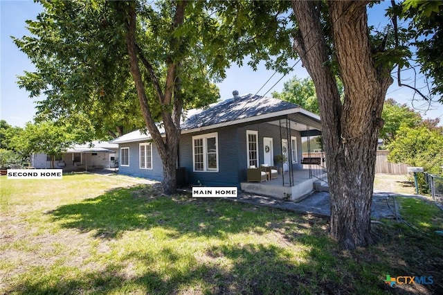 rear view of property with a lawn and fence