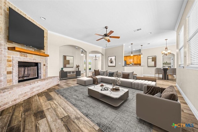 1117 Myrtle Dr, Copperas Cove, TX 76522 - living area with wood finished floors, a chandelier, a brick fireplace, a ceiling fan, and arched walkways