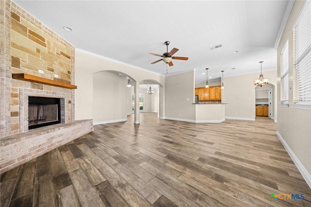 1117 Myrtle Dr, Copperas Cove, TX 76522 - unfurnished living room featuring a chandelier, a fireplace, ceiling fan, light wood finished floors, and arched walkways