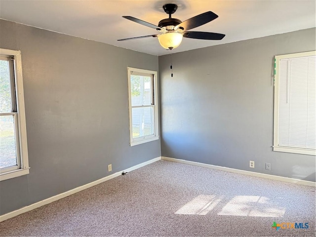 carpeted spare room featuring ceiling fan and a healthy amount of sunlight