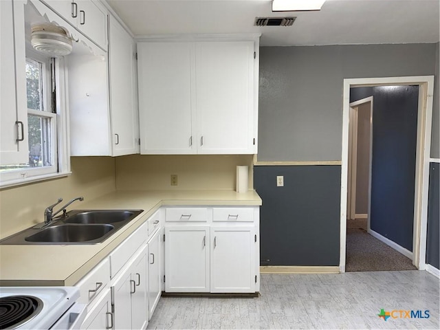 kitchen featuring white electric range, white cabinets, and sink