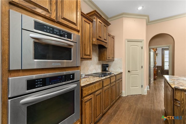 kitchen featuring light stone counters, dark hardwood / wood-style flooring, backsplash, crown molding, and black electric stovetop