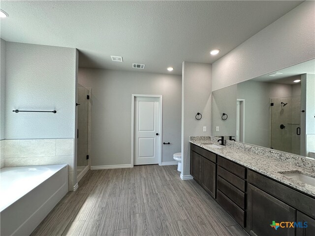 full bathroom featuring independent shower and bath, wood-type flooring, vanity, and toilet