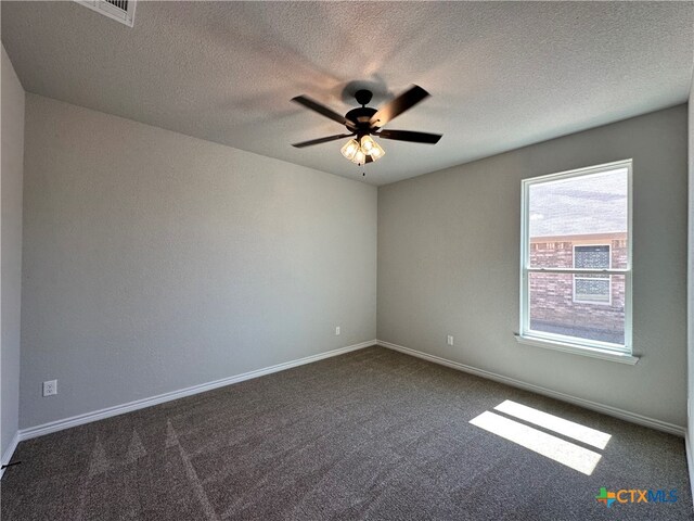 empty room with ceiling fan, a textured ceiling, and dark carpet