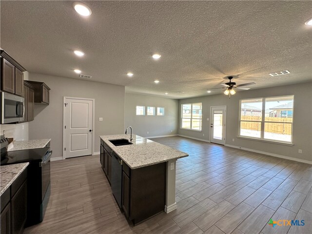 kitchen with stainless steel appliances, a healthy amount of sunlight, light wood-type flooring, and a textured ceiling