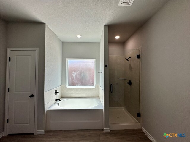 bathroom featuring independent shower and bath, a textured ceiling, and hardwood / wood-style flooring